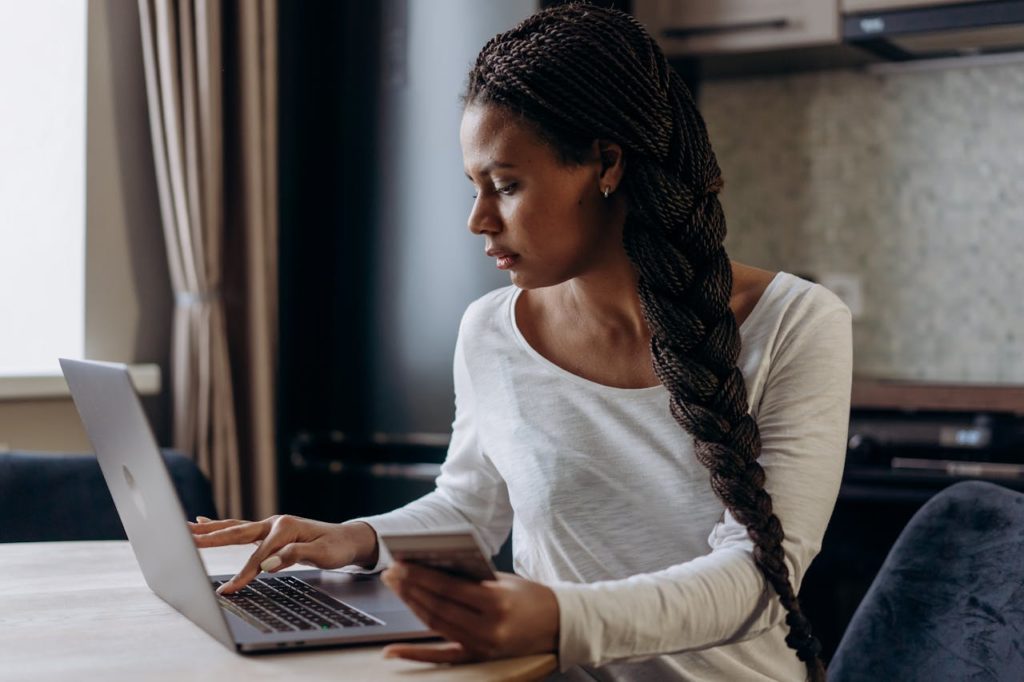 pexels photo 6969796 Young African American woman with braided hair making an online payment using laptop and credit card.